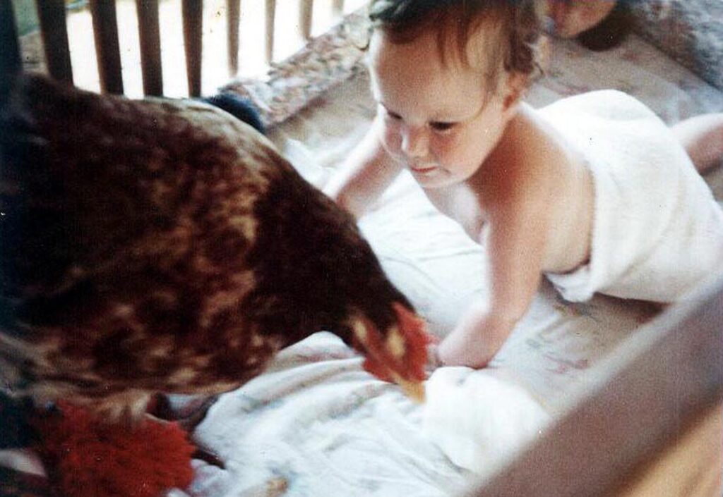 Bryony, Mick & Lucy's firstborn playing with a chicken at home